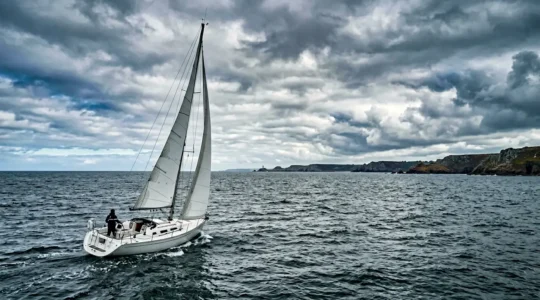 Vue panoramique d'un voilier naviguant dans les eaux bretonnes sous un ciel dynamique