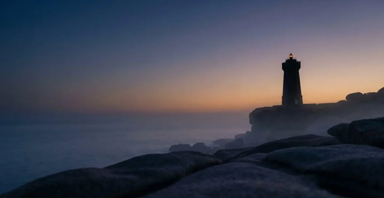 Phare emblématique de Bretagne illuminé au crépuscule émergeant de la brume marine