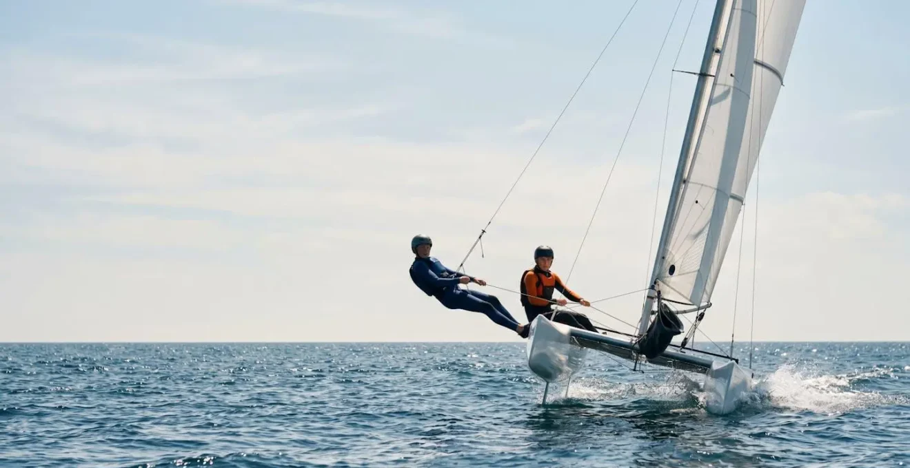 Catamaran de sport naviguant avec une coque légèrement levée au-dessus de l'eau sous ciel lumineux