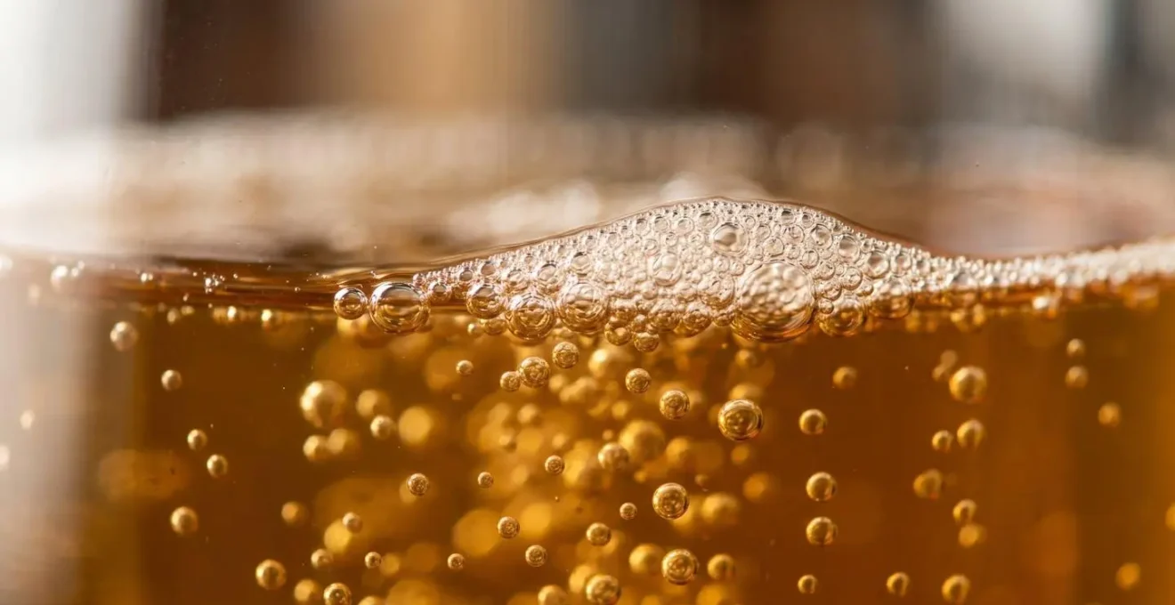 Gros plan détaillé de bulles de fermentation dans du moût de cidre ambré en cuve traditionnelle