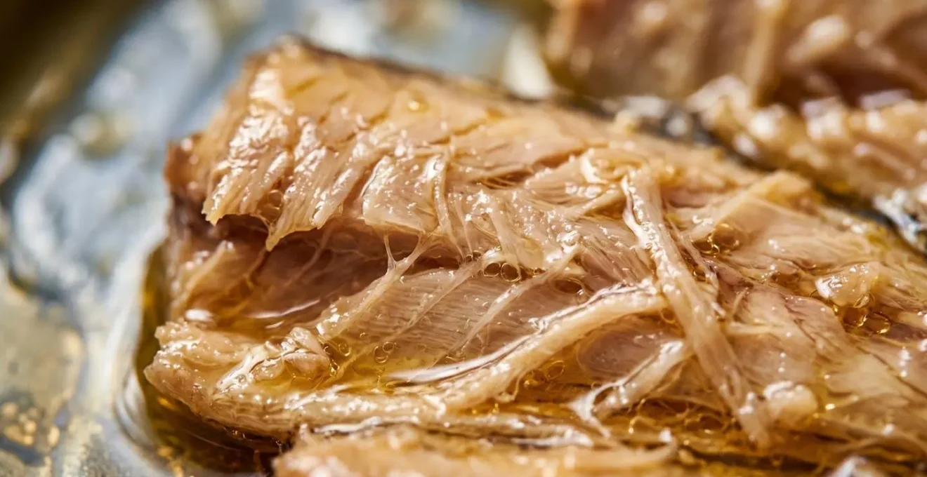Gros plan macro sur la texture confite d'une sardine millésimée dans son huile d'olive dorée