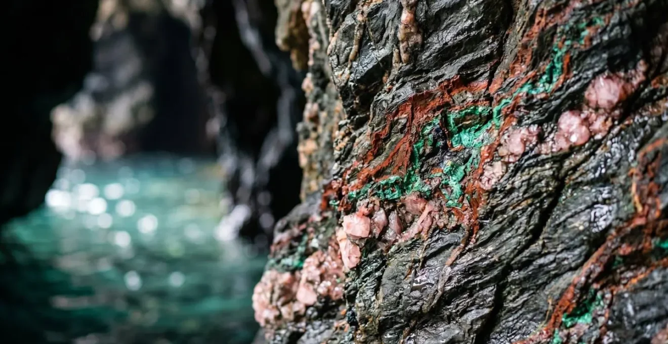 Intérieur d'une grotte marine avec parois rocheuses multicolores et reflets dans l'eau émeraude