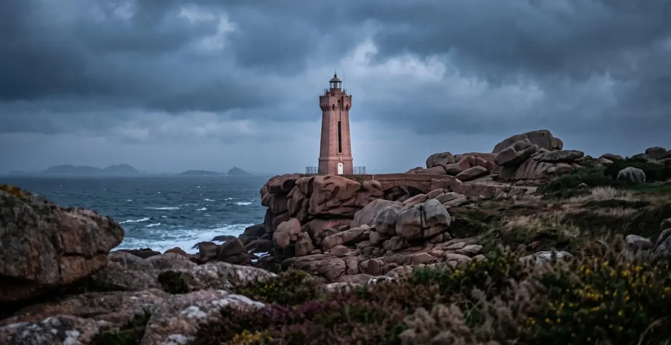 Le phare emblématique de Mean Ruz sur son promontoire de granit rose sous une lumière atmosphérique en Bretagne